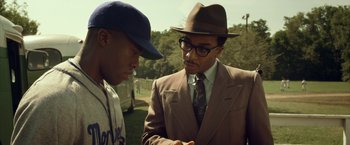 Movie still from “42” (2013), directed by Brian Helgeland – A man in a suit and hat talking to another man in a baseball uniform; Medium shot, Over the shoulder angle
