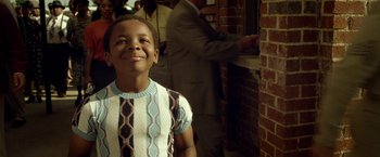Movie still from “42” (2013), directed by Brian Helgeland – A young boy smiling for the camera in front of a brick wall; Close Up shot, Low angle
