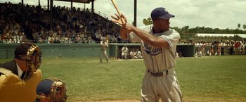 Movie still from “42” (2013), directed by Brian Helgeland – A man holding a baseball bat on top of a baseball field; Medium shot, Over the shoulder angle