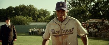 Movie still from “42” (2013), directed by Brian Helgeland – A baseball player is standing on a field; Medium shot, Over the shoulder angle