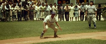 Movie still from “42” (2013), directed by Brian Helgeland – A baseball player kneeling down on a baseball field; Wide shot, High angle