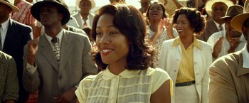 Movie still from “42” (2013), directed by Brian Helgeland – A woman in a yellow dress smiling for the camera; Close Up shot, Over the shoulder angle