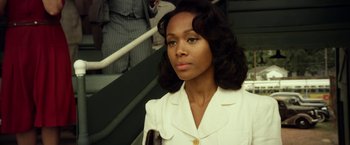 Movie still from “42” (2013), directed by Brian Helgeland – A woman in a white jacket is standing in front of some stairs; Close Up shot, Over the shoulder angle