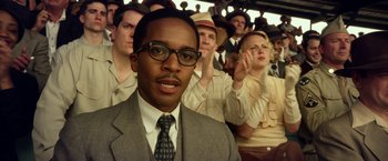 Movie still from “42” (2013), directed by Brian Helgeland – A man in a suit and tie in front of a group of people; Close Up shot, Over the shoulder angle