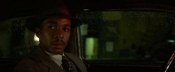 Movie still from “42” (2013), directed by Brian Helgeland – A man in a suit and hat sitting in front of a window; Close Up shot, Over the shoulder angle