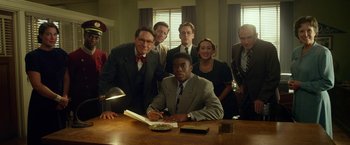 Movie still from “42” (2013), directed by Brian Helgeland – A group of people standing around a man in a business suit; Medium shot, High angle