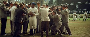 Movie still from “42” (2013), directed by Brian Helgeland – A group of men standing next to each other on top of a field; Wide shot, High angle