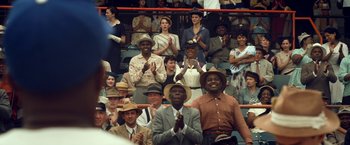 Movie still from “42” (2013), directed by Brian Helgeland – A group of people sitting and standing in a stadium; Medium shot, Over the shoulder angle