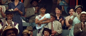 Movie still from “42” (2013), directed by Brian Helgeland – A woman holding a baby in a crowd of people; Medium shot, Over the shoulder angle