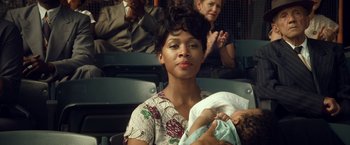 Movie still from “42” (2013), directed by Brian Helgeland – A woman holding a baby in her arms in an audience; Close Up shot, Over the shoulder angle