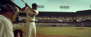 Movie still from “42” (2013), directed by Brian Helgeland – A baseball player holding a bat on top of a baseball field; Wide shot, Over the shoulder angle
