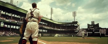 Movie still from “42” (2013), directed by Brian Helgeland – A baseball player standing on top of a baseball field; Wide shot, Low angle