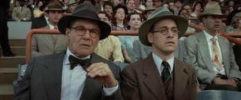 Movie still from “42” (2013), directed by Brian Helgeland – Two men in suits and hats sitting next to each other in front of an audience; Close Up shot, Low angle