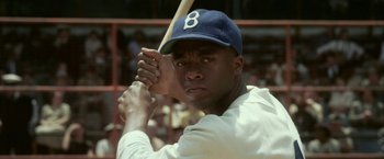Movie still from “42” (2013), directed by Brian Helgeland – A man holding a baseball bat while standing in a field; Close Up shot, Over the shoulder angle