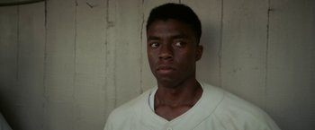 Movie still from “42” (2013), directed by Brian Helgeland – A young man in a white shirt is looking at the camera; Close Up shot, Over the shoulder angle