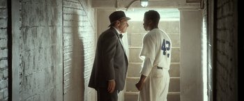 Movie still from “42” (2013), directed by Brian Helgeland – A man in a suit talking to a man in a baseball uniform; Medium shot, Over the shoulder angle