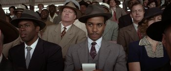 Movie still from “42” (2013), directed by Brian Helgeland – A man in a suit and hat is holding a cell phone; Medium shot, High angle
