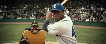Movie still from “42” (2013), directed by Brian Helgeland – A baseball player holding a baseball bat on a field; Medium shot, Over the shoulder angle