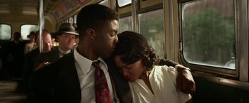 Movie still from “42” (2013), directed by Brian Helgeland – A man and a woman kissing on a train; Medium shot, Low angle