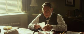 Movie still from “42” (2013), directed by Brian Helgeland – An older man sitting at a table writing on a piece of paper; Medium shot, Low angle