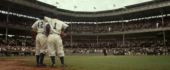 Movie still from “42” (2013), directed by Brian Helgeland – A baseball player standing on top of a baseball field; Wide shot, High angle