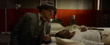Movie still from “42” (2013), directed by Brian Helgeland – An older man in a suit and hat talking to a young man in a hospital bed; Medium shot, Low angle