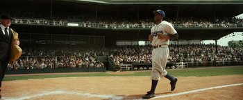 Movie still from “42” (2013), directed by Brian Helgeland – A baseball player walking across a baseball field; Wide shot, Low angle