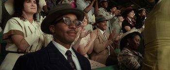 Movie still from “42” (2013), directed by Brian Helgeland – A group of people in suits and hats clapping; Close Up shot, Over the shoulder angle