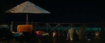 Movie still from “47 Meters Down” (2017), directed by Johannes Roberts – A person sitting on a deck at night with an umbrella; Extreme Wide shot, High angle