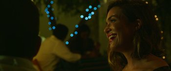 Movie still from “47 Meters Down” (2017), directed by Johannes Roberts – A person smiling at night with lights in the background; Close Up shot, Over the shoulder angle
