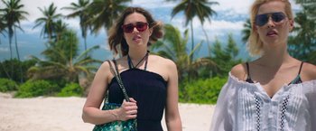 Movie still from “47 Meters Down” (2017), directed by Johannes Roberts – A woman wearing sunglasses and a black dress on the beach; Medium shot, Over the shoulder angle