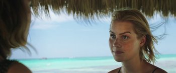 Movie still from “47 Meters Down” (2017), directed by Johannes Roberts – A beautiful young woman standing under a straw umbrella; Close Up shot, Over the shoulder angle