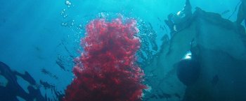 Movie still from “47 Meters Down” (2017), directed by Johannes Roberts – A red blob of liquid floating in the ocean; Extreme Wide shot, Overhead angle