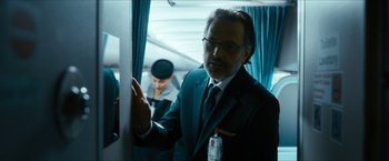 Movie still from “7500” (2019), directed by Patrick Vollrath – A man in a suit and tie standing next to a window; Close Up shot, Over the shoulder angle