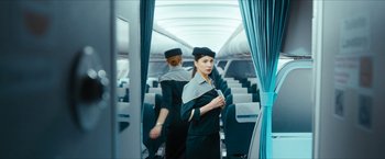 Movie still from “7500” (2019), directed by Patrick Vollrath – Two flight attendants are standing in the aisle of an airplane; Medium shot, High angle