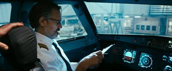 Movie still from “7500” (2019), directed by Patrick Vollrath – A man sitting in an airplane cockpit looking at a tablet; Medium shot, Low angle