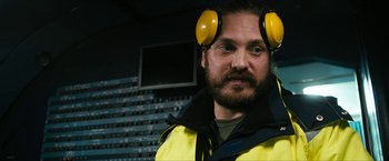 Movie still from “7500” (2019), directed by Patrick Vollrath – A man wearing ear muffs in a recording studio; Close Up shot, Over the shoulder angle