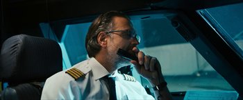 Movie still from “7500” (2019), directed by Patrick Vollrath – A man in a uniform talking on a cell phone while sitting in a car; Close Up shot, Low angle
