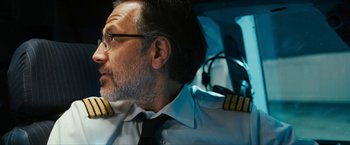 Movie still from “7500” (2019), directed by Patrick Vollrath – A man wearing a pilot's uniform sitting in a car; Close Up shot, Low angle