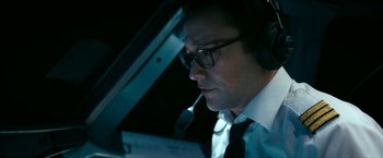 Movie still from “7500” (2019), directed by Patrick Vollrath – A man wearing glasses and a tie is sitting at a desk; Close Up shot, Low angle