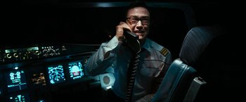 Movie still from “7500” (2019), directed by Patrick Vollrath – A man talking on a phone while wearing glasses; Medium shot, High angle