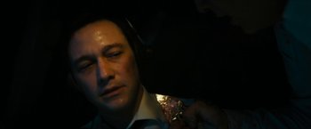 Movie still from “7500” (2019), directed by Patrick Vollrath – A man wearing a tie and headphones in a dark room; Close Up shot, Overhead angle