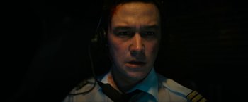 Movie still from “7500” (2019), directed by Patrick Vollrath – A man wearing a tie and headphones looking at the camera; Close Up shot, High angle