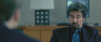 Movie still from “88 Minutes” (2007), directed by Jon Avnet – A man wearing a suit and tie sitting in front of a tv; Close Up shot, Over the shoulder angle