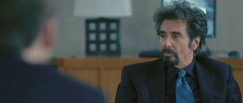 Movie still from “88 Minutes” (2007), directed by Jon Avnet – A man in a suit and tie sitting in front of a lamp; Close Up shot, Over the shoulder angle