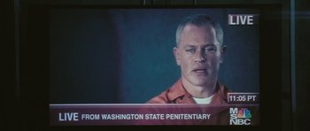 Movie still from “88 Minutes” (2007), directed by Jon Avnet – A man in an orange shirt is in front of a television; Close Up shot, Low angle