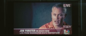 Movie still from “88 Minutes” (2007), directed by Jon Avnet – A man in an orange prison uniform on a television screen; Close Up shot, Over the shoulder angle