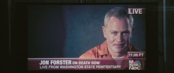 Movie still from “88 Minutes” (2007), directed by Jon Avnet – A man in an orange prison uniform on a television screen; Close Up shot, Over the shoulder angle