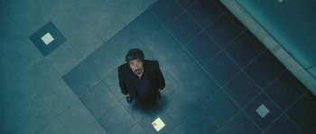Movie still from “88 Minutes” (2007), directed by Jon Avnet – A man standing on a tiled floor looking up at the camera; Wide shot, Overhead angle