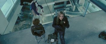Movie still from “88 Minutes” (2007), directed by Jon Avnet – A woman standing next to a chair in a room; Wide shot, Overhead angle